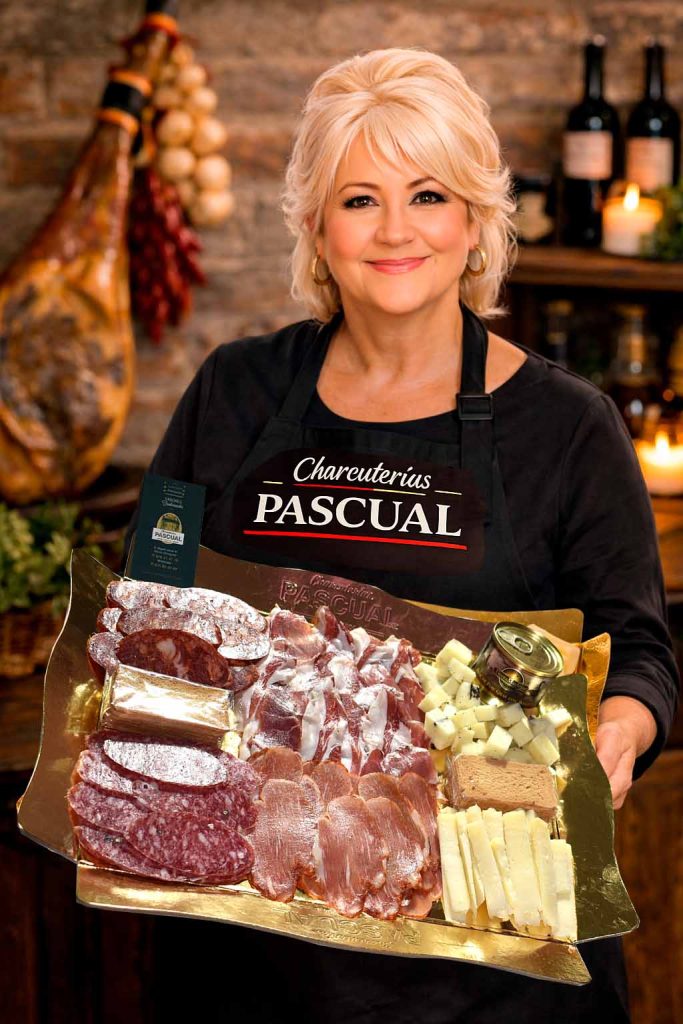 Imagen de Marisol en Charcuterías Pascual presentando una bandeja gourmet con ibéricos y quesos. Ideal para acompañar la guía “Bandejas gourmet para regalar” y reforzar la selección artesana y el asesoramiento en tienda.